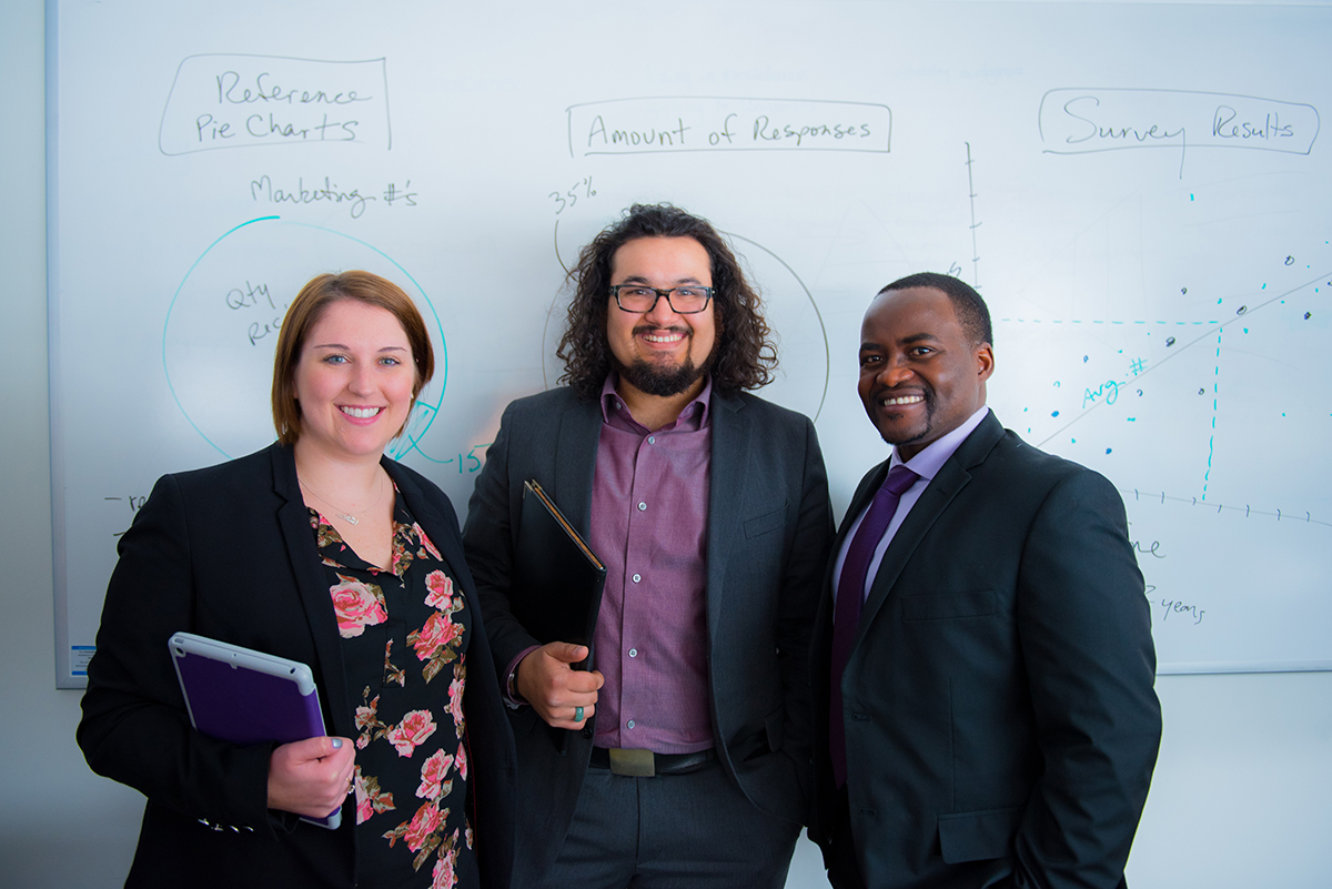 Two students standing with professor