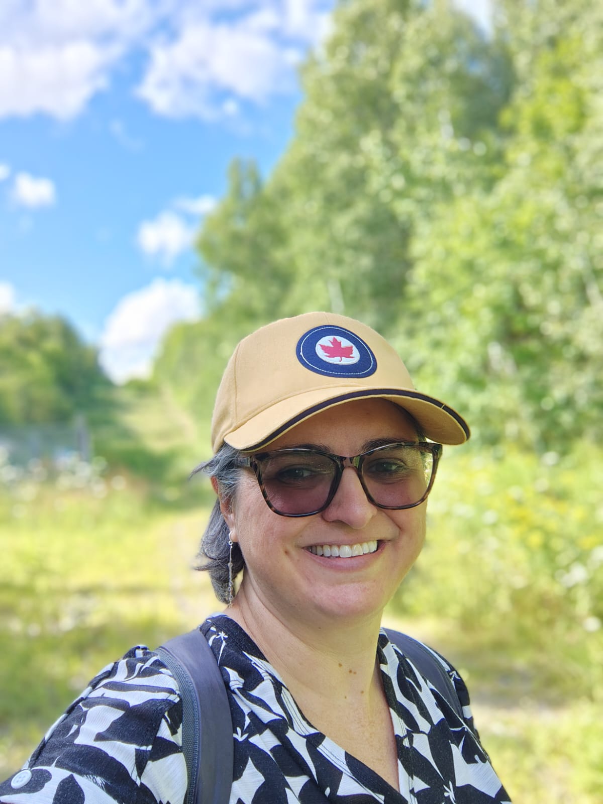 A woman wearing a cap taking a picture against a nature background