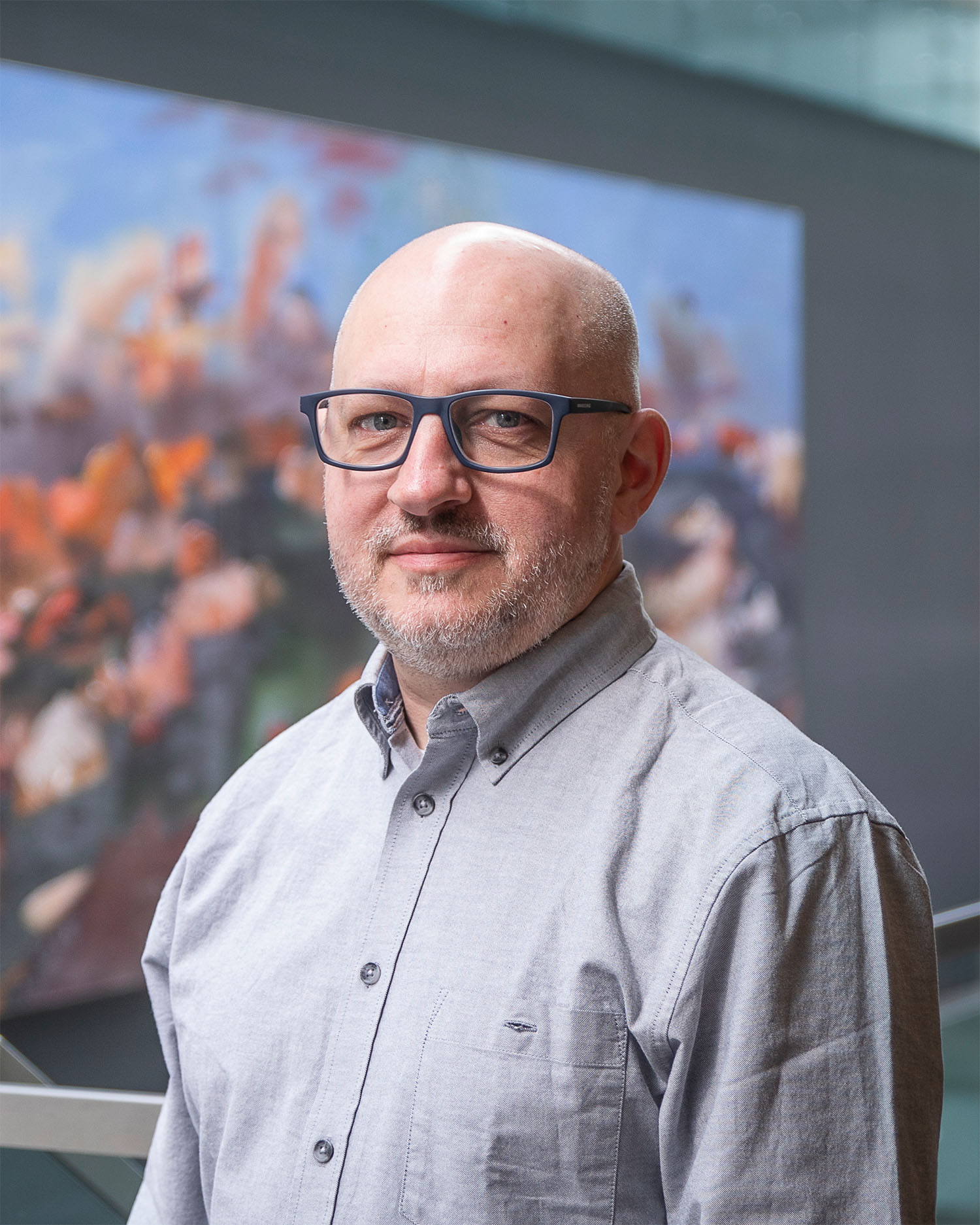 A man in gray shirt standing with the interior background of the library in view