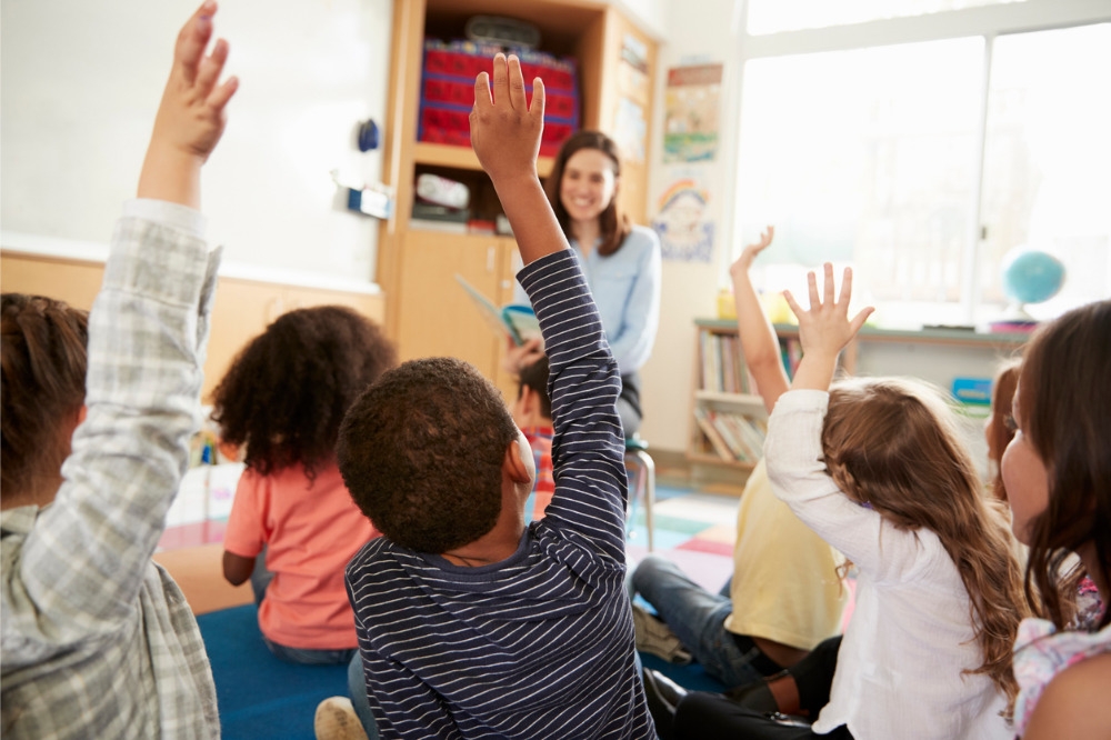 a group of students raising their hands in front of a teacher