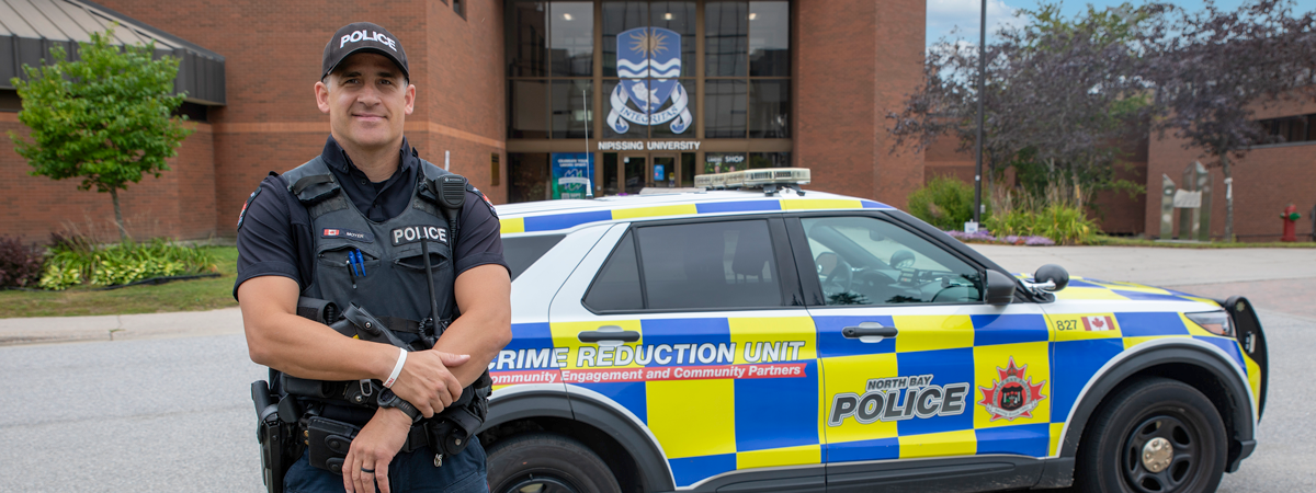 Constable Moyer standing in front of his vehicle in the front entrance