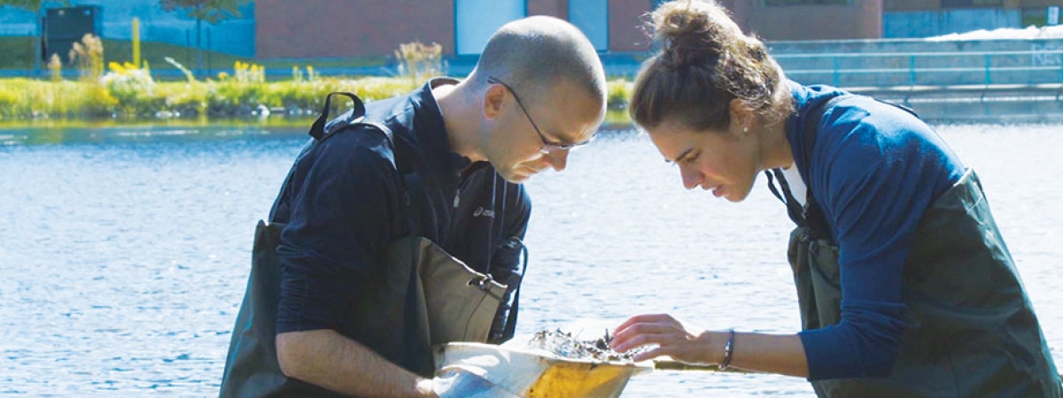 student and professor examining aquatic life in the pond