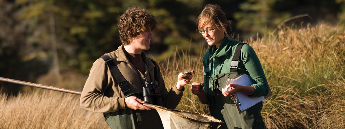 student in hip-waders study pond life