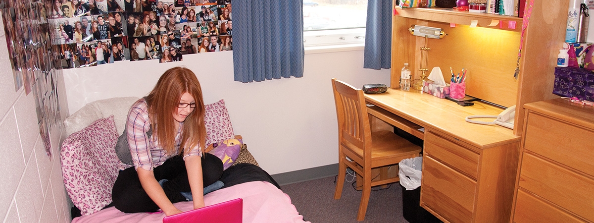 student with laptop in bedroom
