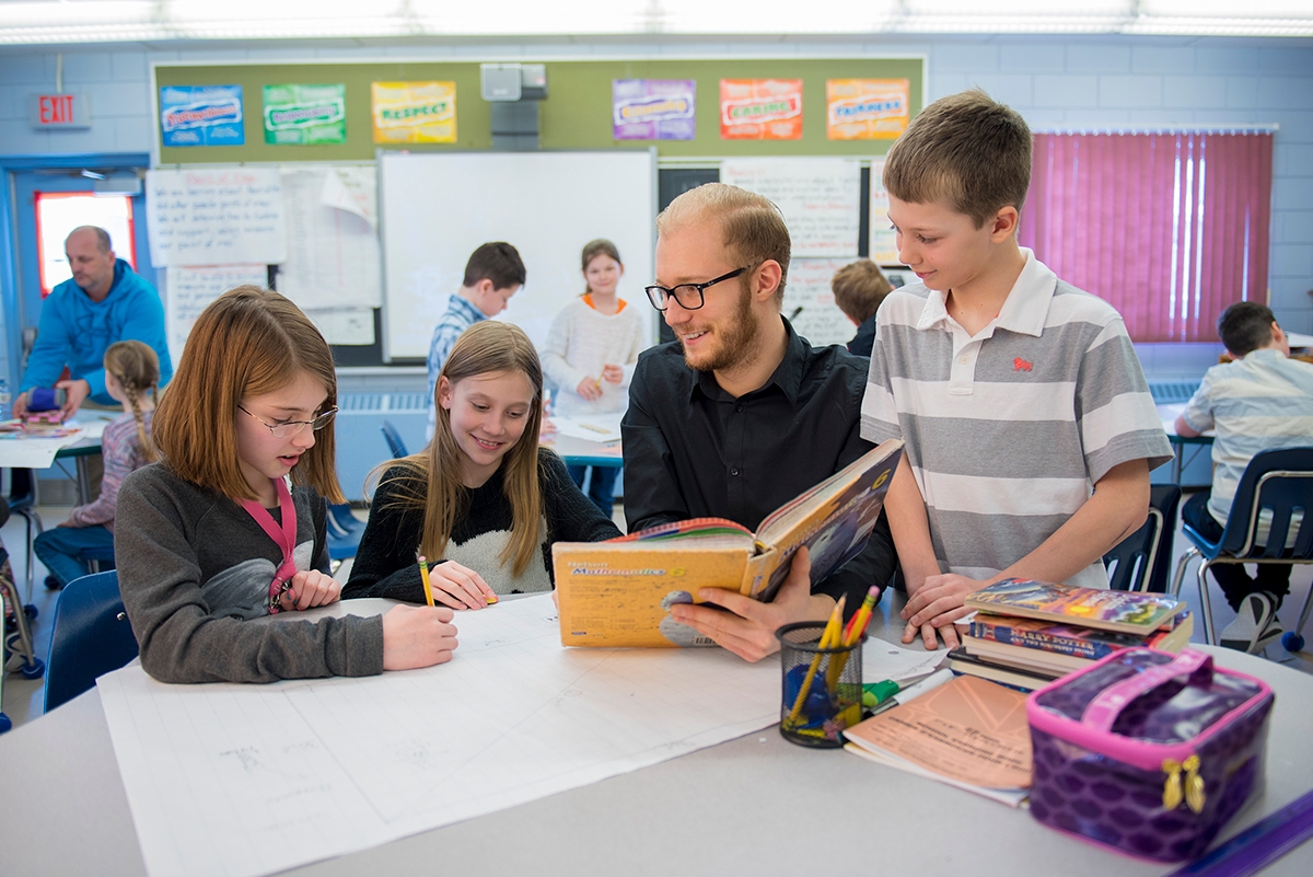 A teacher sitting and talking with 3 other students at the table