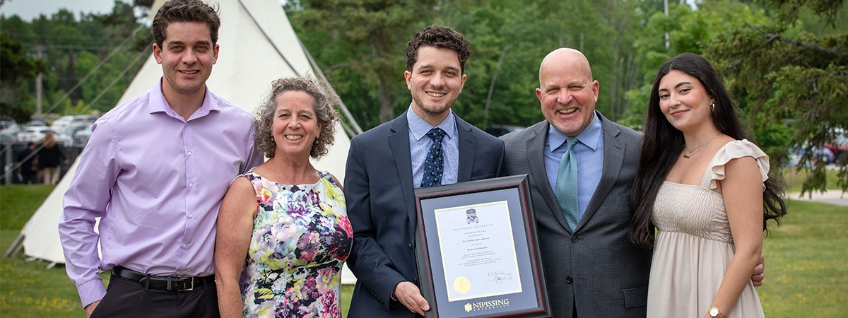Family with graduate holding degree frame