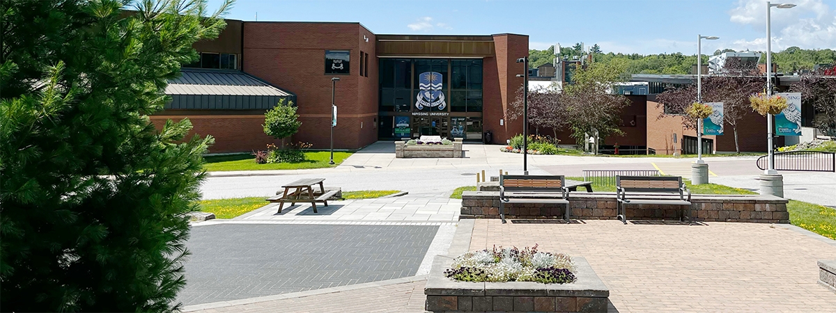 Spring photo of the main doors and plants around Nipissing University on a sunny day