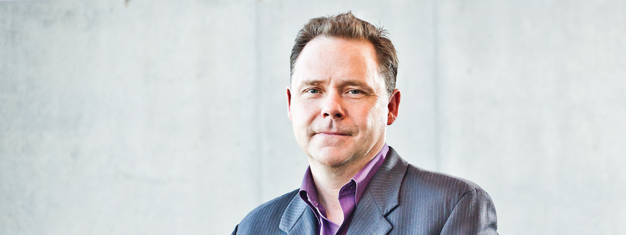 Dr. Glen Sharpe sitting in front of a light neutral background. 