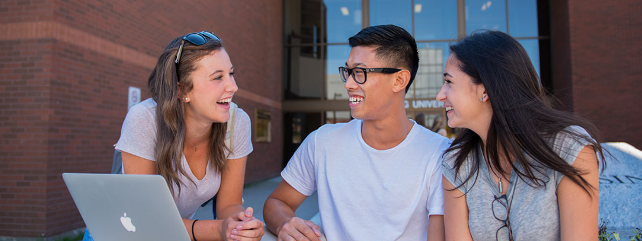 Students sitting in front of the NU main entrance talking and laughing