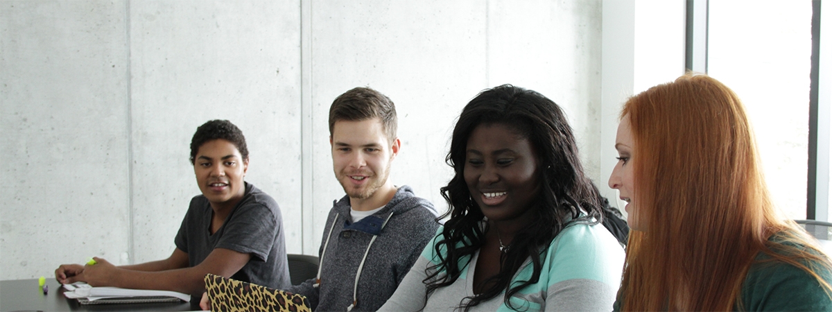 Four students seated together smiling at each other.