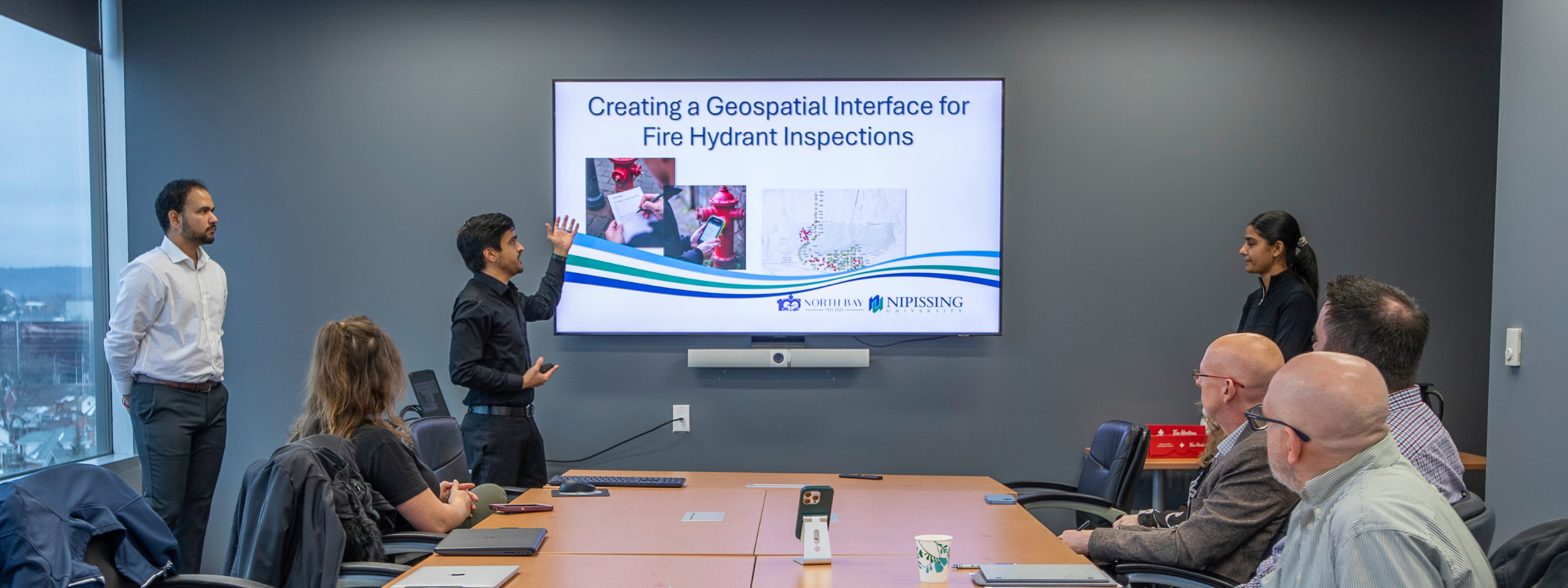 Keshav Singh, Lovepreet Kaur, and Sagar Tewatia presenting their GIS projects in the CIty Hall Executive Boardroom