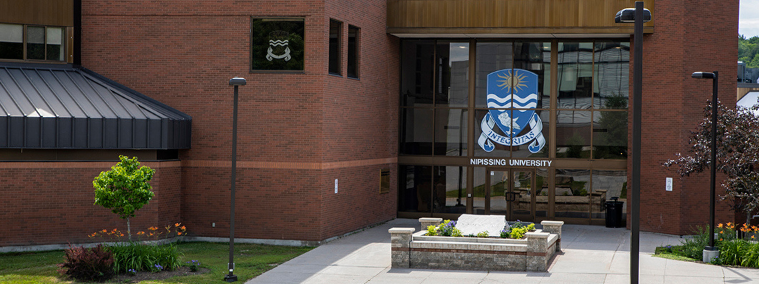 The front entrance of Nipissing University with gardens 