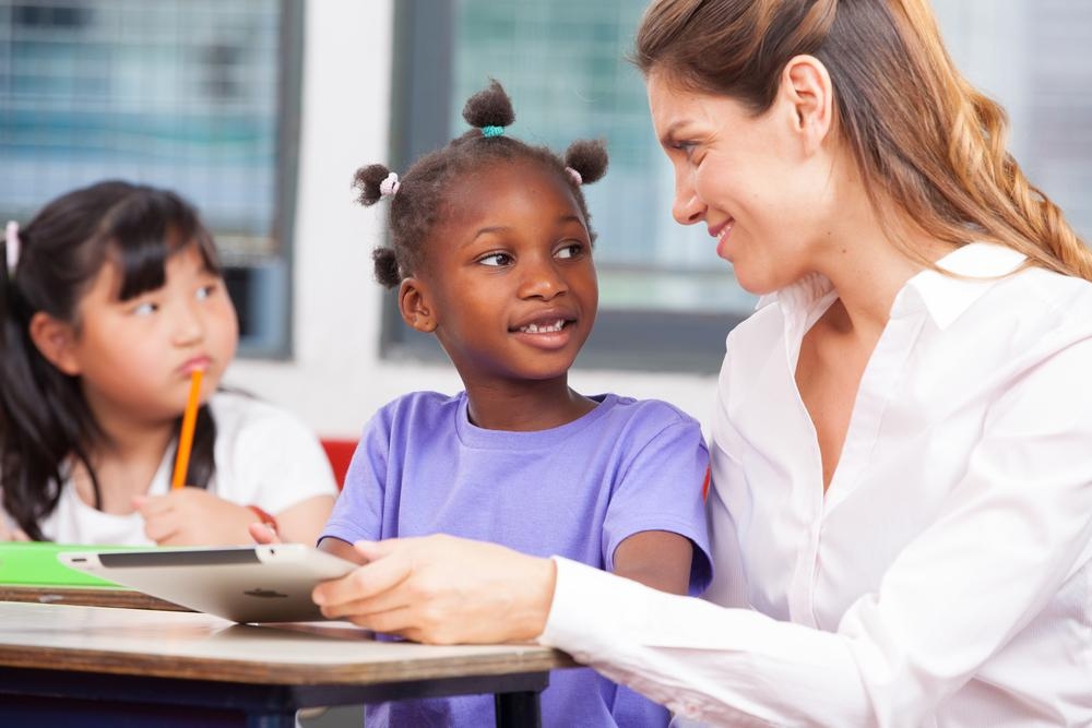 A teacher sitting next to her small student