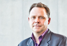 Dr. Glen Sharpe sitting in front of a light neutral background. 