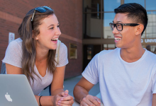 Students sitting in front of the NU main entrance talking and laughing