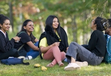 A group of international students sitting in a forested area on Nipissing University Campus.