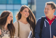 four students talking with the campus library in the background