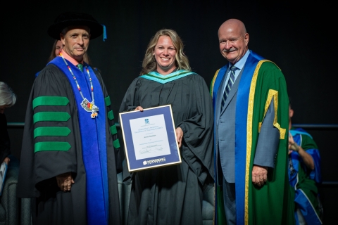 Anna Pearson receiving her award on stage from Dr. Wamsley and Dr. Cook