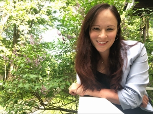 Rachel leaning on a deck with a forested background