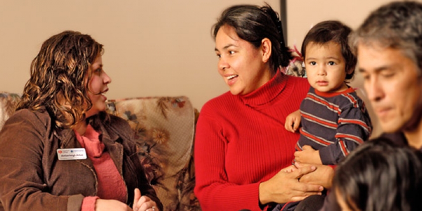a nursing student conversing with a young family 